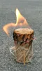 A burning fire starter log sits on a textured gray surface. Produktbild-Vorschau