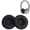 Two black ear pads for headphones are shown in the foreground, with a pair of grey headphones in the background. Produktbild-Vorschau