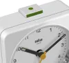 A close-up view of the top part of a white Braun alarm clock, showing the alarm button and part of the clock face with hands. Podgląd zdjęcia produktu