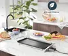 A kitchen counter with a grill, bread, vegetables, and a sink. Voir les images du produit