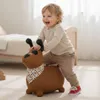 A young child is playing with a brown dog-shaped inflatable toy in a room. Produktbild-Vorschau