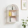 A white arched shelf with two wooden shelves mounted on a white wall. The shelf contains decorative items. Produktbild-Vorschau