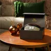A WoodWick candle in a gift box is placed on a wooden coffee table, next to decorative vases. Podgląd zdjęcia produktu