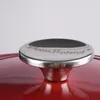 A close-up of the lid of a red pot, showing the handle. Produktbild-Vorschau