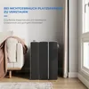 A folded mattress is shown next to a sofa with a blanket draped over it, in a room with a window and curtains. Produktbild-Vorschau