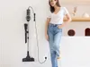 A woman stands next to a vacuum cleaner that is plugged into the wall and mounted on the wall. Podgląd zdjęcia produktu