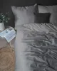 A neatly made bed with dark gray striped satin bedding. Produktbild-Vorschau