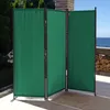 A green, three-panel room divider is set up on an outdoor patio with a view of the ocean. Produktbild-Vorschau