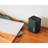 A black GoPro dual battery charger is placed on a wooden table next to a stack of books. Anteprima dell’immagine prodotto