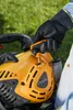 A person's gloved hand is shown operating a pull-start mechanism on a yellow and black leaf blower. Produktbild-Vorschau