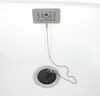 A close-up view of a sink drain with a stopper and chain, and an overflow grate above it. Produktbild-Vorschau
