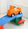 A child's ride-on toy car on a blue slide and green play structure. Voir les images du produit
