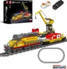 A detailed product shot of a building block train set, including a locomotive, cargo cars, a crane, and accessories like a remote control and battery pack, displayed on a white background with a circular track. Náhľad obrázku produktu