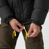 A close-up of a person adjusting the drawstring on a black jacket. Produktbild-Vorschau