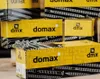 Several yellow boxes of DMX screws are stacked on a wooden surface. Produktbild-Vorschau