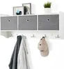 A white wall-mounted hall tree with three gray fabric storage bins and five metal hooks, with two coats and a baseball cap hanging from the hooks. Voir les images du produit
