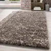 A shaggy rug is shown in a room with a brick wall and a bookshelf in the background. Produktbild-Vorschau