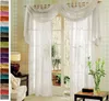 A set of white voile curtains with a decorative swag draped across the top, shown in a room setting with a door and window. Produktbild-Vorschau