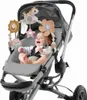 A baby sitting in a stroller with a toy arch attached. Produktbild-Vorschau
