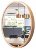 A round wooden mirror reflecting a modern living/dining area with furniture and pendant lights. Anteprima dell’immagine prodotto
