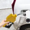 A hand holding a yellow fuel pump nozzle, inserting it into the fuel tank of a white car. Produktbild-Vorschau