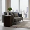 A modern living room with a sofa and a wooden side table in front of a large window with a city view. Náhled obrázku produktu