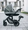 A stroller is parked on a paved walkway in front of a building. Náhľad obrázku produktu