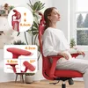 A woman is sitting in a red ergonomic office chair, with her eyes closed and a relaxed expression. The chair has adjustable armrests and a headrest. Insets show close-ups of the chair's features with measurements. Produktbild-Vorschau