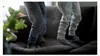 Two children's legs in sweatpants and socks jumping on a couch. Produktbild-Vorschau