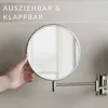 A hand is shown adjusting a wall-mounted cosmetic mirror. Produktbild-Vorschau