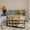 A woman sitting on a sofa with coffee tables in front of her. Anteprima dell’immagine prodotto