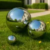 Three polished stainless steel garden spheres of different sizes are placed on a green lawn in front of a modern house. Produktbild-Vorschau