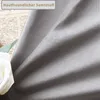 A close-up of gray velvet fabric with a white rose and green leaf in the foreground, and a newspaper in the background. Produktbild-Vorschau