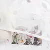 A close-up view of a white sheer curtain with a floral burnout pattern, partially covering a bouquet of roses. Produktbild-Vorschau