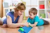 A woman and a child are playing a board game on the floor. Anteprima dell’immagine prodotto