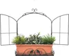 A black metal window frame with a brown planter box filled with green artificial plants. Produktbild-Vorschau