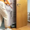 A person is using a foldable drying rack next to a wooden door. Náhled obrázku produktu