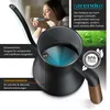 A woman is enjoying a cup of tea while a close-up of a black kettle with a wooden handle is shown, highlighting its features. Náhled obrázku produktu