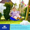 A young girl is happily swinging on a blue swing set in a backyard. Produktbild-Vorschau