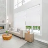 A modern living room with a fireplace, sofa, and large windows covered by white blinds. Voir les images du produit