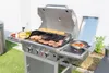 A gas grill with burgers and buns cooking on the grates, and vegetables in a pan on the side burner. Náhled obrázku produktu