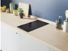 A modern kitchen countertop with an induction hob and various kitchen accessories. Voir les images du produit