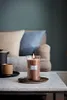 A lit candle sits on a marble table next to a mug and a teapot, with a sofa and pillows in the background. Produktbild-Vorschau