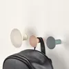 Three wall hooks in different colors are mounted on a white wall. A black backpack is hanging from the middle hook. Anteprima dell’immagine prodotto