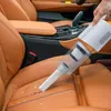 Weißer und oranger Handstaubsauger wird verwendet, um Krümel von einem braunen Ledersitz zu entfernen Produktbild-Vorschau