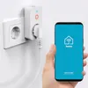 A hand holds a smartphone displaying a smart home app next to a smart plug inserted into a wall socket. Náhľad obrázku produktu