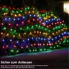 A net of colorful lights is draped over a bush at night. Produktbild-Vorschau