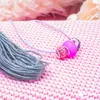 A close-up of craft supplies including a strand of gray thread and a necklace with pink and purple beads on a pink knitted surface. Podgląd zdjęcia produktu
