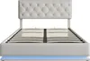 A white upholstered bed frame with a tufted headboard and a slatted mattress support is shown against a white background. Blue LED lighting is visible along the base of the bed frame. Produktbild-Vorschau