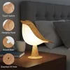 A bird-shaped lamp is placed on a bedside table next to a bed. Anteprima dell’immagine prodotto